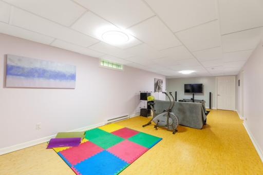 Finished lower level with open rec room space, drop ceiling, and bright overhead lighting