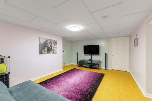 Lower level rec room with space for a TV and media setup, drop ceiling, and bright LED lighting