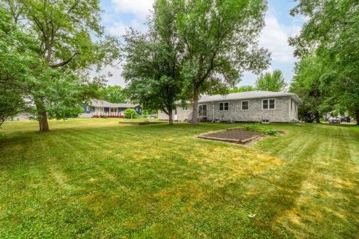 Large backyard with raised garden bed and mature shade trees