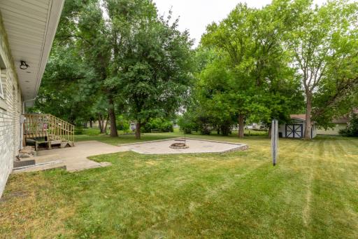 Backyard with fire pit area, rear steps, and mature trees
