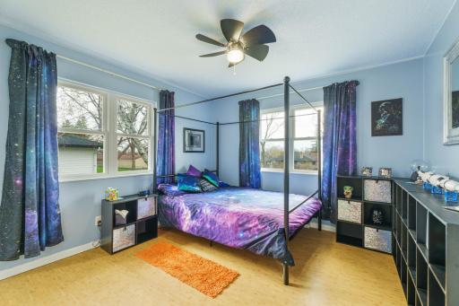 Bedroom with windows on two walls, ceiling fan, and plenty of natural light