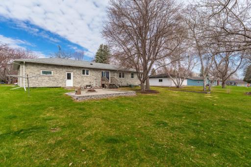 Rear of home with raised patio, fire pit, and spacious backyard
