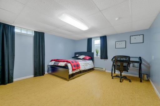 Lower level bedroom with window, open floor space, and room for a desk or workspace