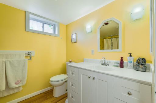 Lower level bathroom with white vanity, storage cabinets, and window for natural light
