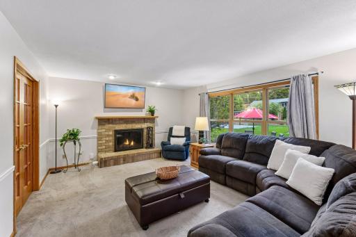 Inviting main-level family room with a wood-burning fireplace and large windows overlooking the backyard