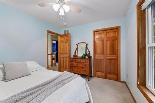 Bright upper-level bedroom with generous closet space and warm natural woodwork