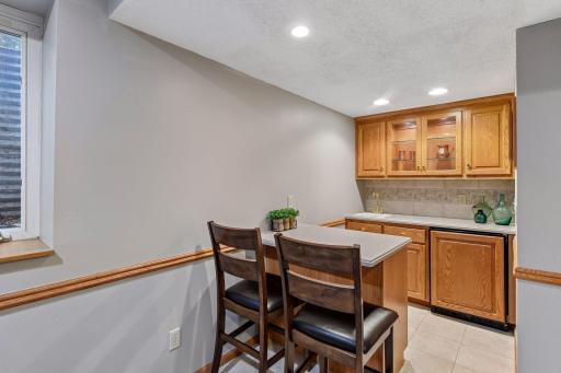 Convenient lower-level wet bar with cabinetry, counter seating and additional space for entertaining