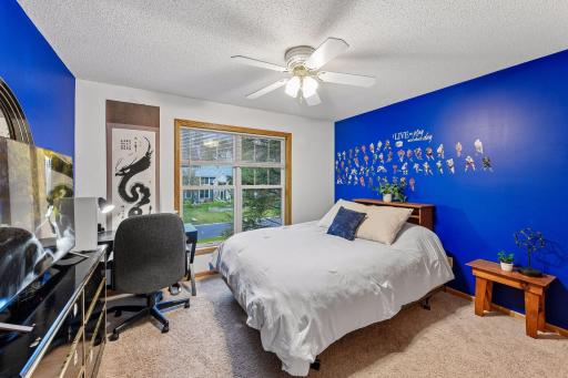 Versatile fourth upper-level bedroom with a large window overlooking the backyard