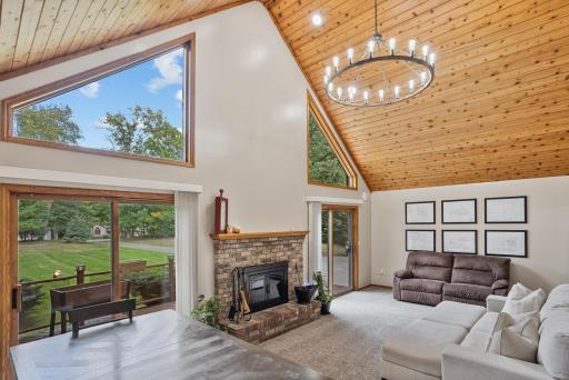 Walls of windows bring the outdoors in, while the fireplace and vaulted wood ceiling create a warm, inviting place to gather.