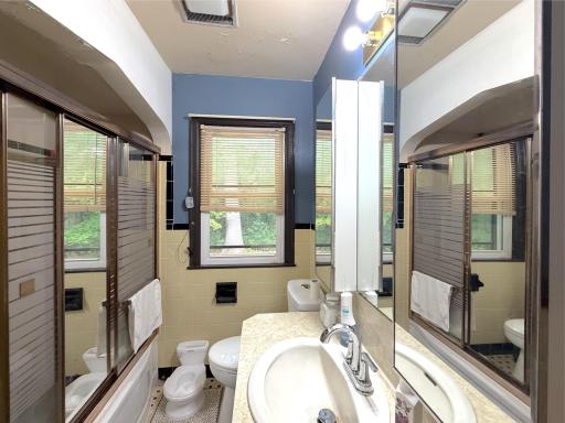Main-level full bathroom features a tub/shower combination, vanity and a window bringing in natural light, centrally located between the bedrooms.