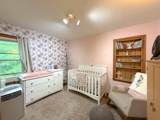 Second main-level bedroom offers a comfortable space with a large window and built-in shelving for added storage and display.