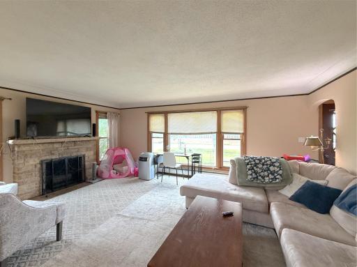 Spacious living room offers plenty of room to gather, with large windows filling the space with natural light and views of the level lawn.