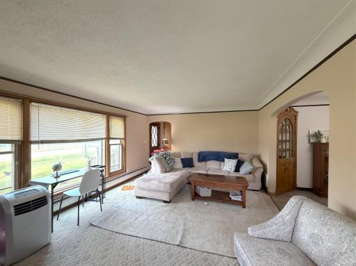 A wall of windows brightens the living room while offering views of the spacious yard while coved ceilings give the room a custom touch.