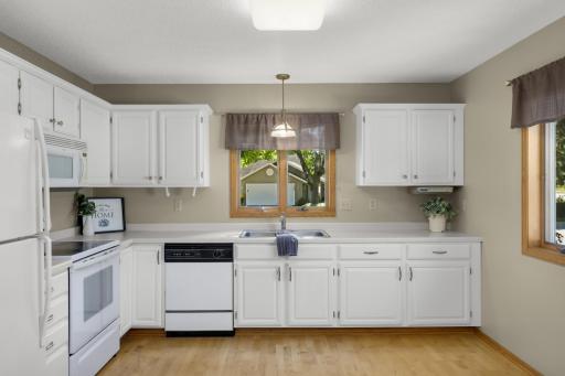 Spacious Kitchen with white cabinetry, plenty of counter space and maple hardwood floors.