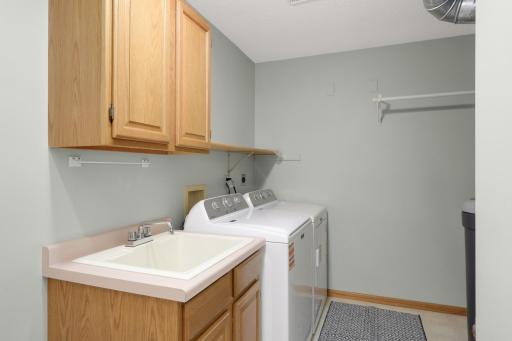 Large main-floor Laundry Room with utility sink, cabinetry and additional storage space.