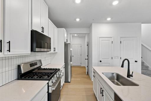 A subway tile backsplash atop the 5-burner gas cooktop with an overhead microwave meets style with functionality