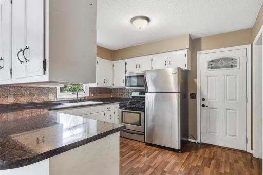 Kitchen area featuring laminate flooring, abundant cabinetry, stainless-steel appliances