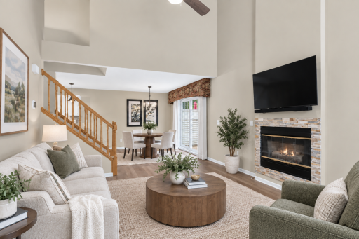 Light-filled living room with vaulted ceiling and gas fireplace. Digitally Staged