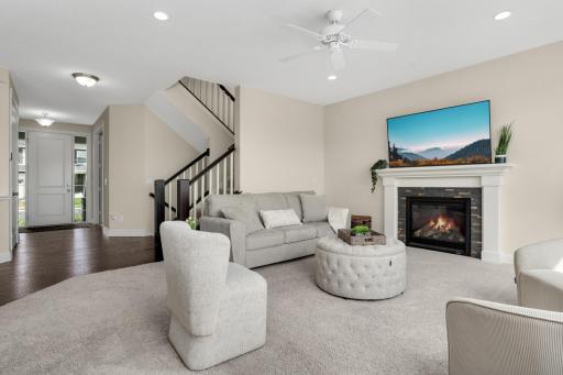 Spacious living room with cozy fireplace and open flow to entry and staircase.