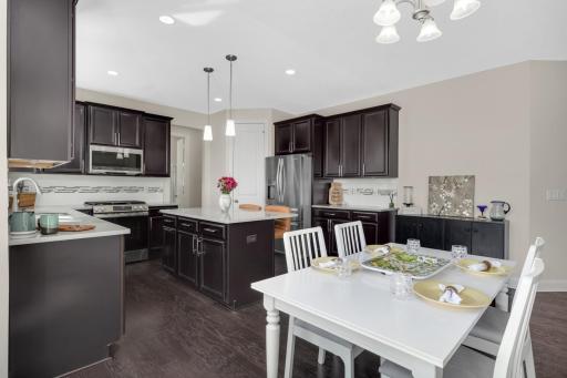 Open-concept kitchen and dining with large center island, dark cabinetry, and seamless flow for entertaining.