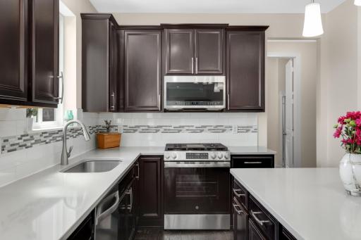 Kitchen featuring stainless steel range, tile backsplash, and rich cabinetry with ample storage.