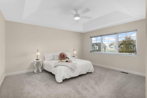 Spacious upper-level primary bedroom with tray ceiling, abundant natural light, and private retreat feel.