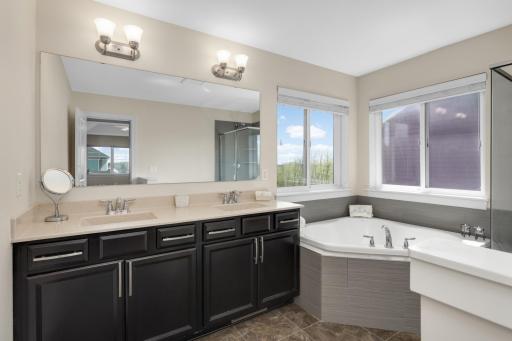 Primary bathroom featuring dual vanities, soaking tub, and natural light.