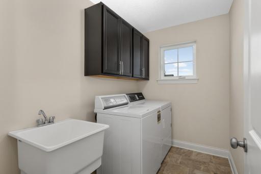 Upper-level laundry room with utility sink, cabinetry, and natural light for everyday convenience.