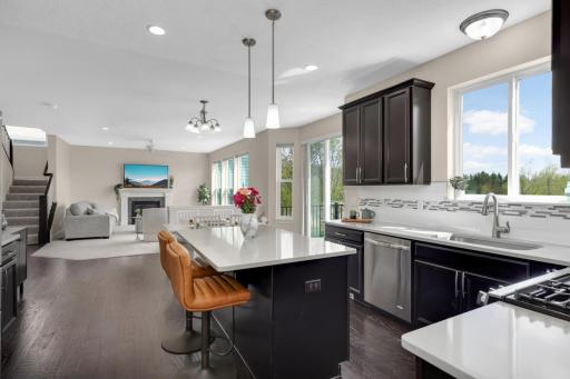 Open kitchen with quartz countertops, large center island, and views into the living room with walkout to deck.