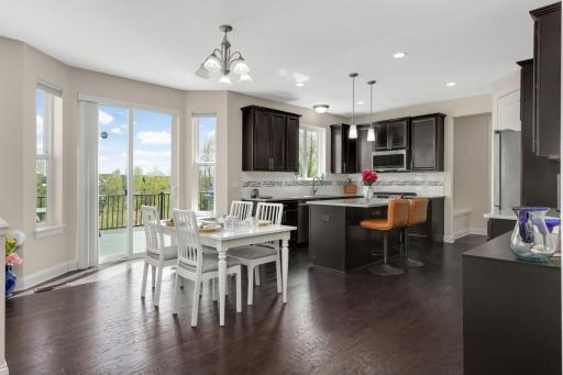 Open-concept kitchen and dining area with center island, dark cabinetry, and walkout to deck with scenic views.