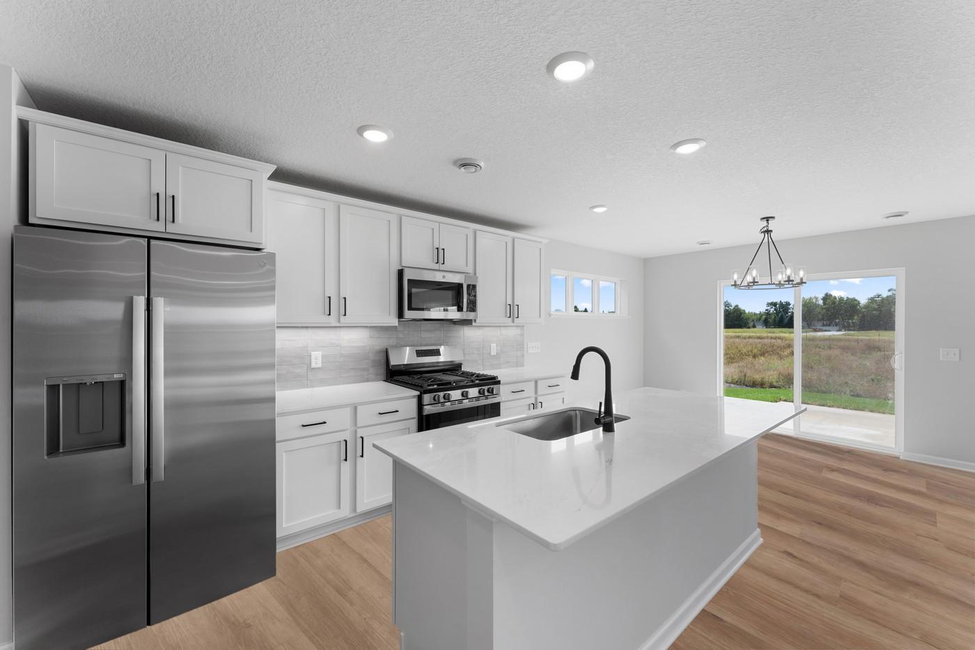 Gorgeous kitchen with quartz countertops, tile backsplash, all appliances included, microwave vented to exterior, black fixtures and hardware.