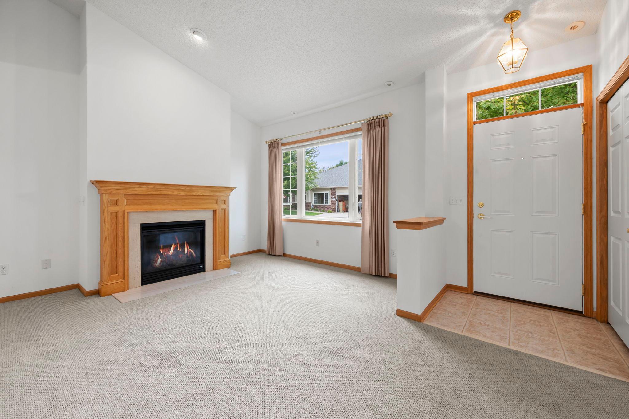 The bright, airy living room features 12-foot vaulted ceilings and a gas fireplace, creating an open welcoming living space.