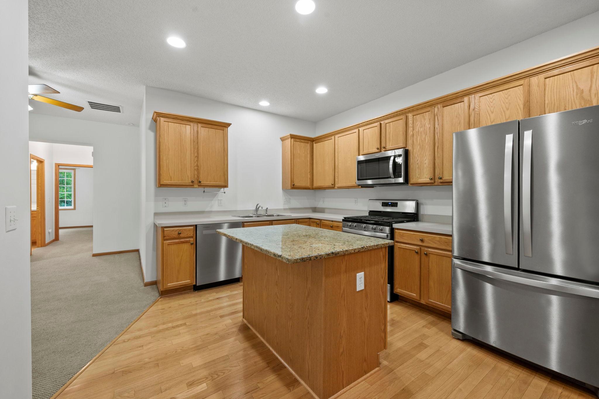 The kitchen features hardwood floors, generous solid wood cabinetry and trim, and a center island with a granite countertop. New stainless steel appliances complete the space.