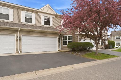 Inviting front exterior highlighted by blooming trees, maintenance-free siding, and a welcoming private entrance.