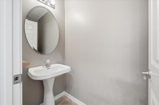 Convenient main-level half bath featuring neutral finishes and an updated vanity with pedestal sink.