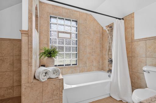The oversized primary bath features a full tiled tub and shower surround.