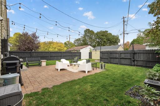 The fully fenced backyard features a freshly stained privacy fence, paver patio and landscape lighting.