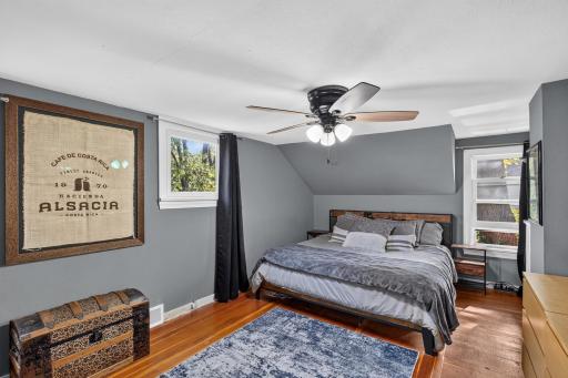 Primary bedroom, wood floors, lots of windows, ceiling fan.