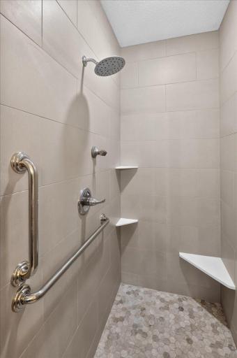 Primary walk-in tile shower with grab bars