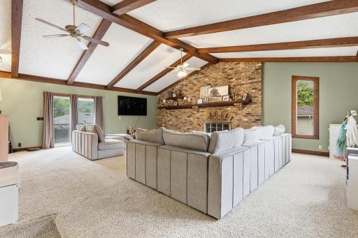 The heart of the home - this stunning great room offers vaulted ceilings, warm wood beams highlighting the ceiling, and a floor to ceiling brick fireplace.