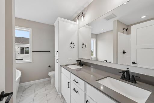 Private Primary bath with dual vanities, fiberglass shower and LVP flooring.