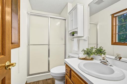 Private 3/4 bath, located within the primary suite, complete with a new light fixture and new laminate flooring.