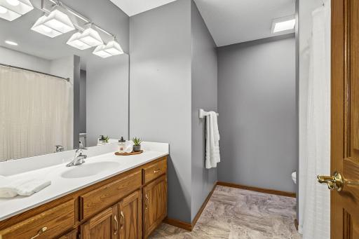 Updated upper level full bath with a single sink, tile floor, raised toilet, and a tile bath surround.