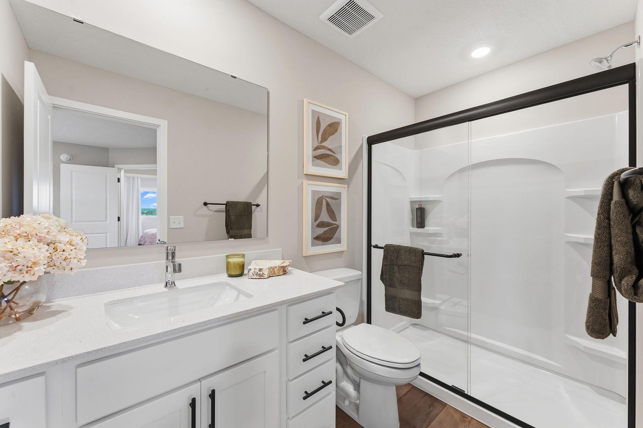 The private bathroom includes a stylish single vanity with built-in cabinetry and a glass-enclosed shower