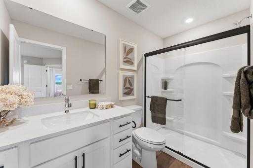 The private bathroom includes a stylish single vanity with built-in cabinetry and a glass-enclosed shower