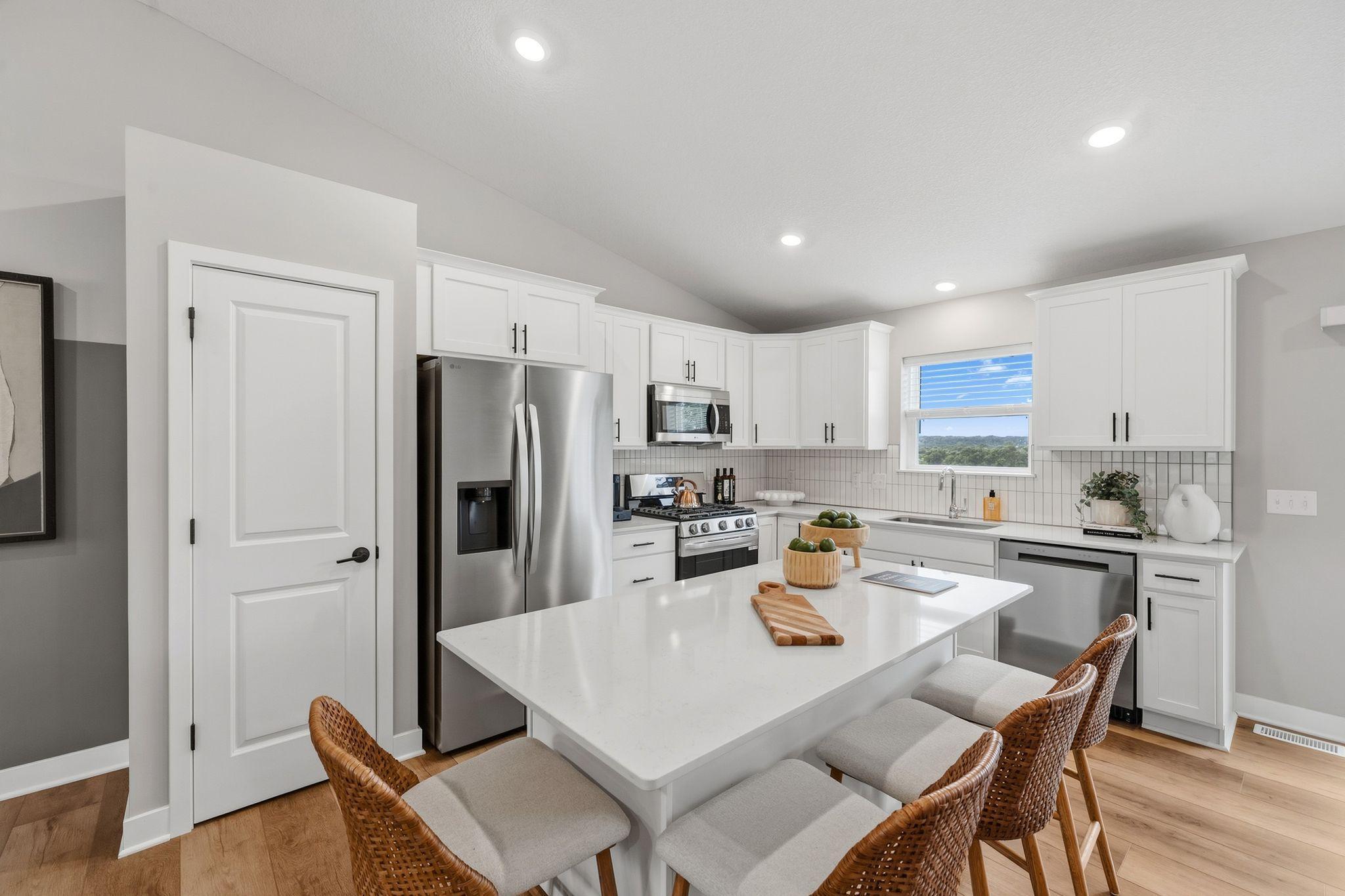 The kitchen is stylish and functional with sleek cabinetry, brand-new stainless steel appliances and a multifunctional center island with bar-style seating.