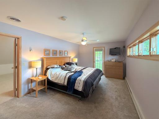 Spacious upper-level primary bedroom offering plenty of room to unwind, with soft natural light and a private door leading outside.