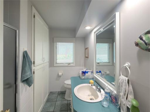 Main-level three-quarter bathroom featuring a walk-in shower, generous vanity space and built-in cabinetry for extra storage.
