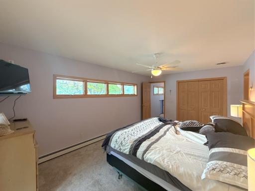 Generously sized primary bedroom featuring a row of windows, ample closet space and plenty of room for additional furnishings.