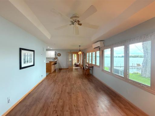 Bright lakeside living and dining area where large windows frame the water from nearly every angle. The open layout offers flexibility for creating separate dining and gathering spaces.